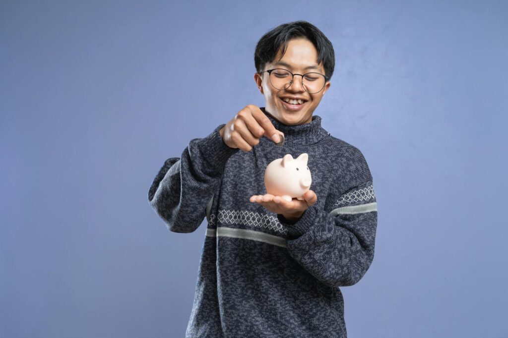 A close-up shot of a hand placing a coin into a white ceramic piggy bank, symbolizing saving money.