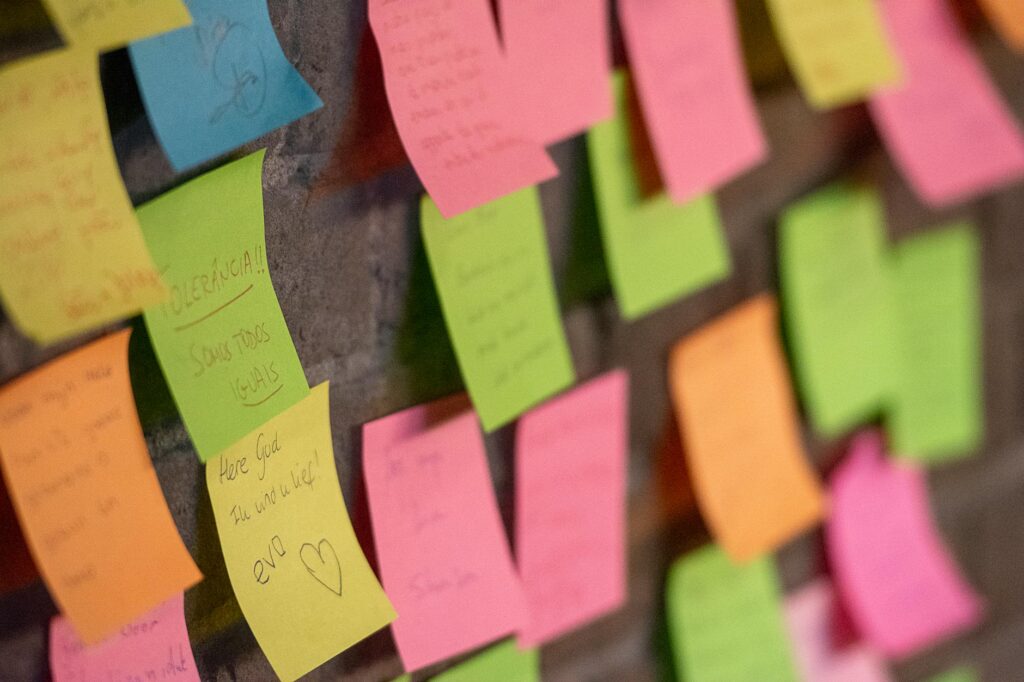 A creative student entrepreneur stands in front of a wall covered in colorful sticky notes, planning their business strategy.