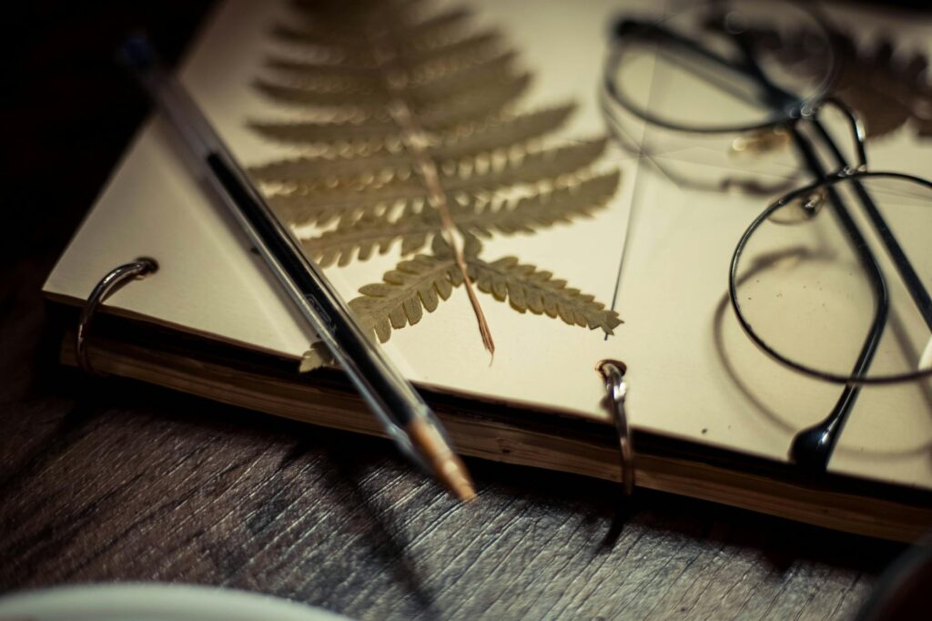 A top-down view of an organized study space, featuring an open notebook, a steaming cup of coffee, and stylish eyeglasses on a wooden desk.