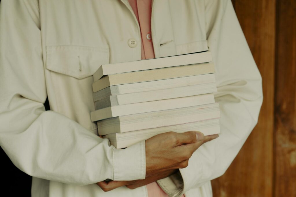 An overwhelmed student sitting in front of a large stack of textbooks, illustrating study burnout.