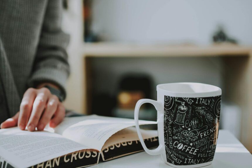 A stressed college student sits at a messy desk, holding their head in their hands, surrounded by books and a laptop.