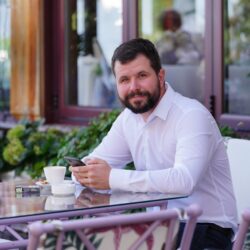 A young adult in their 20s looking thoughtfully at a stock market app on their smartphone.