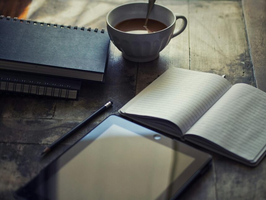 A focused student writing in a weekly planner with textbooks and a laptop nearby.