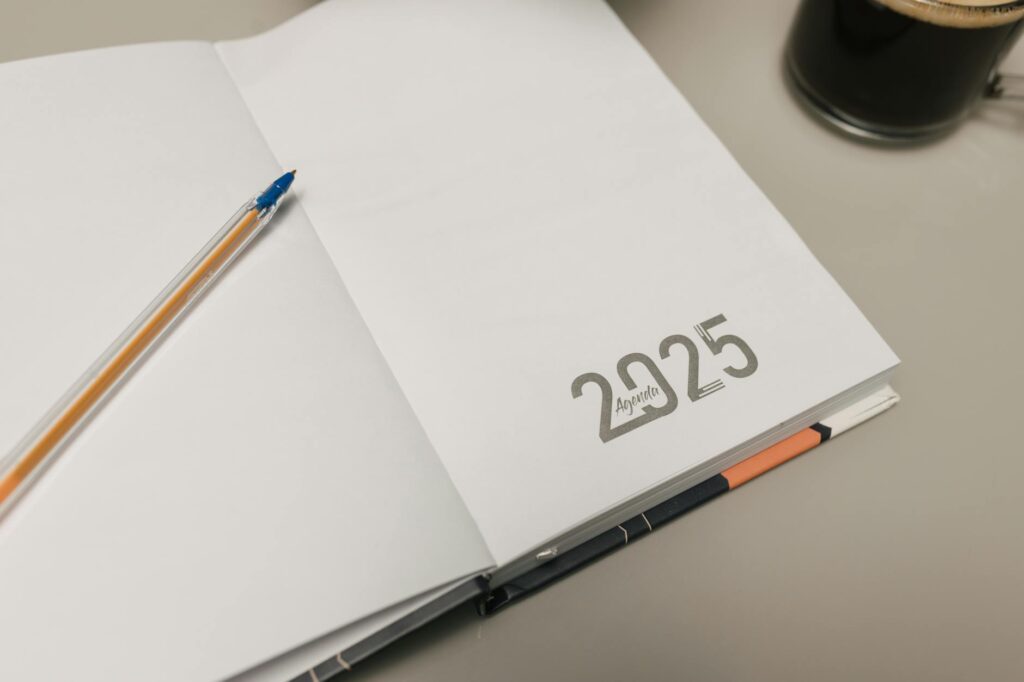 An overhead shot of a neatly organized desk featuring a weekly schedule, a cup of coffee, and a pen.