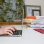 A diligent student sitting at a well-lit desk, surrounded by open textbooks and a laptop, focused on their studies.