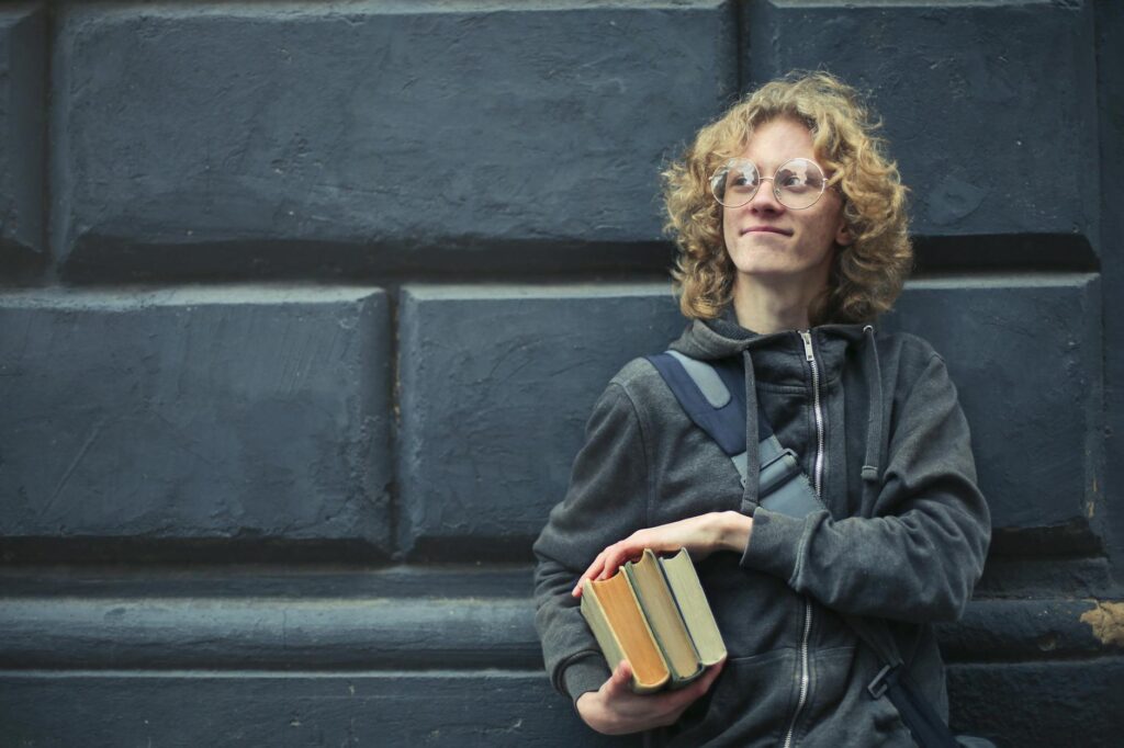 A stressed student with their head in their hands, surrounded by a large, messy pile of textbooks before applying the 80/20 rule.