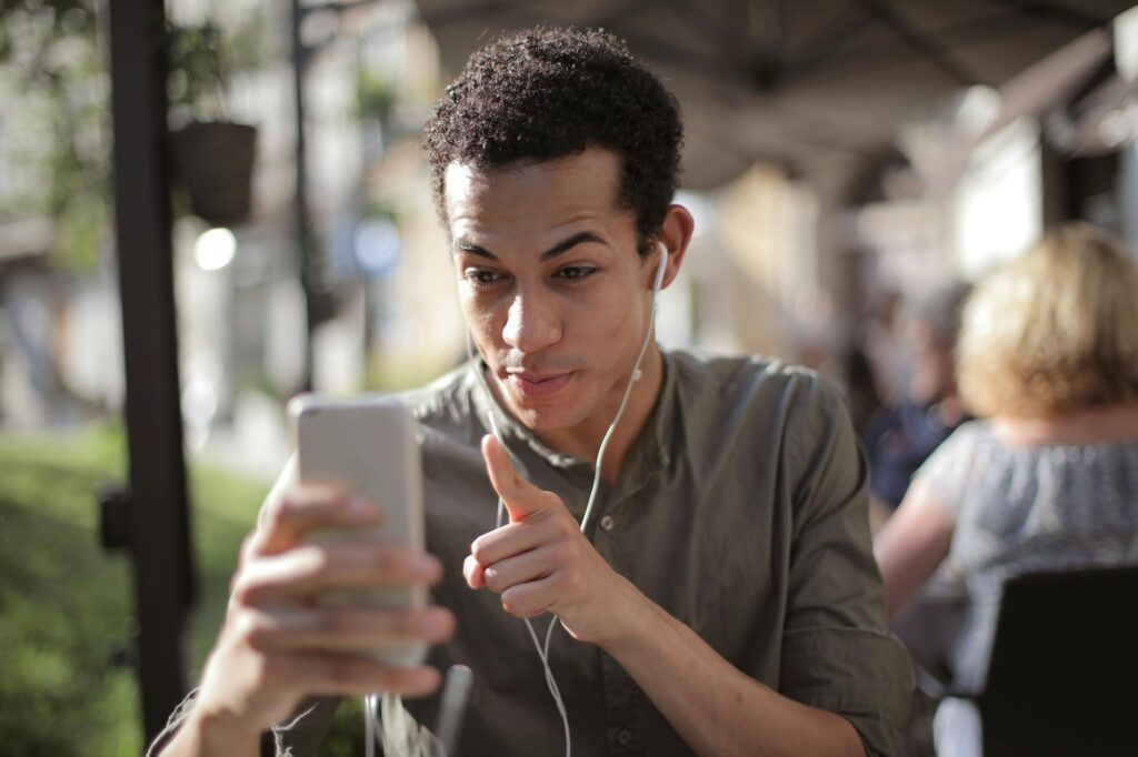 A young person smiling as they use a mobile banking app on their smartphone to pay a bill.