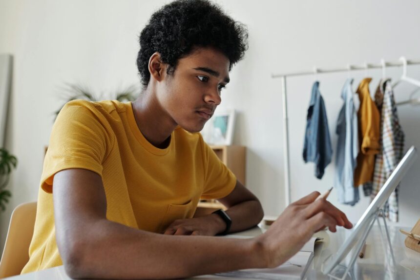 A focused college student studying at a desk with a lamp, surrounded by books and notes.