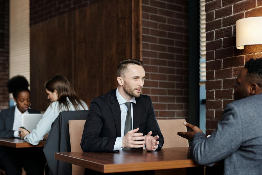 Two diverse young friends sitting at a cafe, smiling and talking about their financial future.