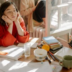 A frustrated student sits at a desk covered in disorganized, chaotic lecture notes.