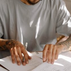 A stressed student with their head in their hands, surrounded by a pile of textbooks and illuminated by a single desk lamp late at night.