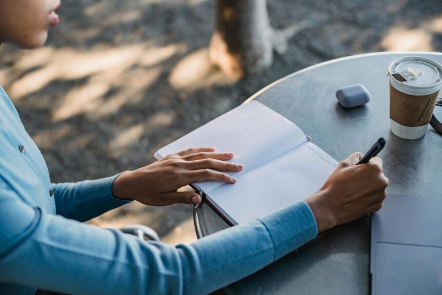 A determined college freshman studies for their future internship while sitting in a bright, modern coffee shop.