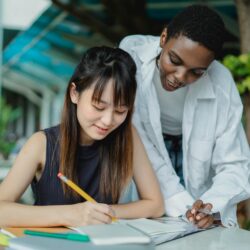 A focused student surrounded by open textbooks and a glowing lamp, studying late into the night.