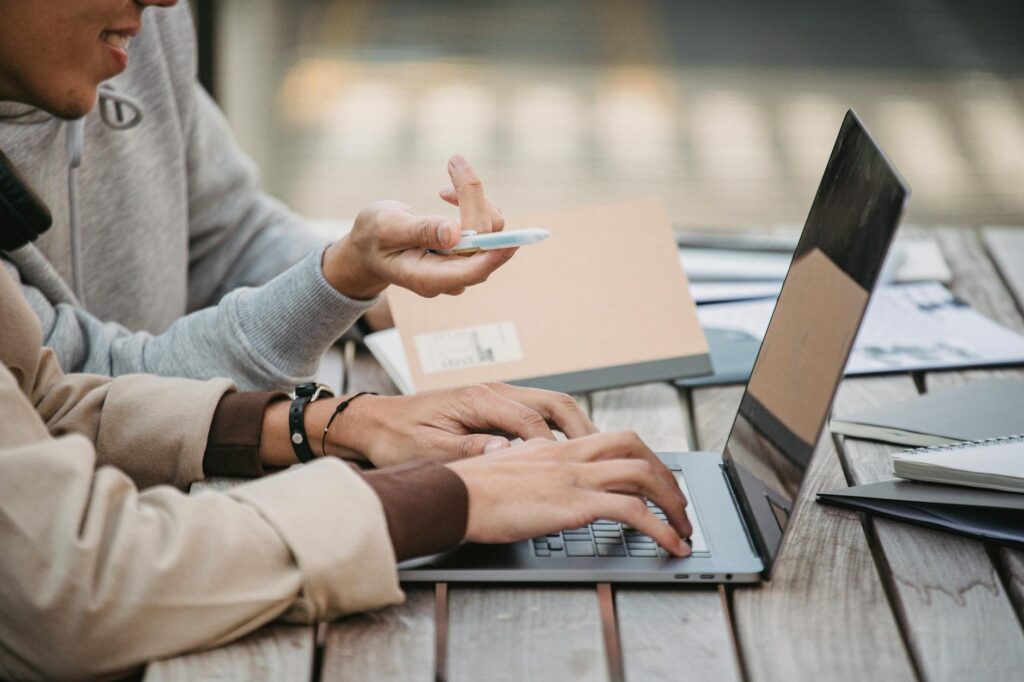 A person focused on their personal budget, with a laptop showing a spreadsheet and a notebook for calculations.