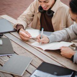 A university student diligently time-blocking their week in a planner with colorful pens.