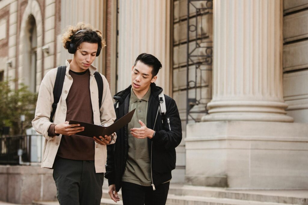 A focused college student using a pen to mark dates on a physical weekly planner.