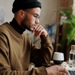 A focused student organizes their weekly schedule on a laptop next to a physical planner and a cup of coffee.