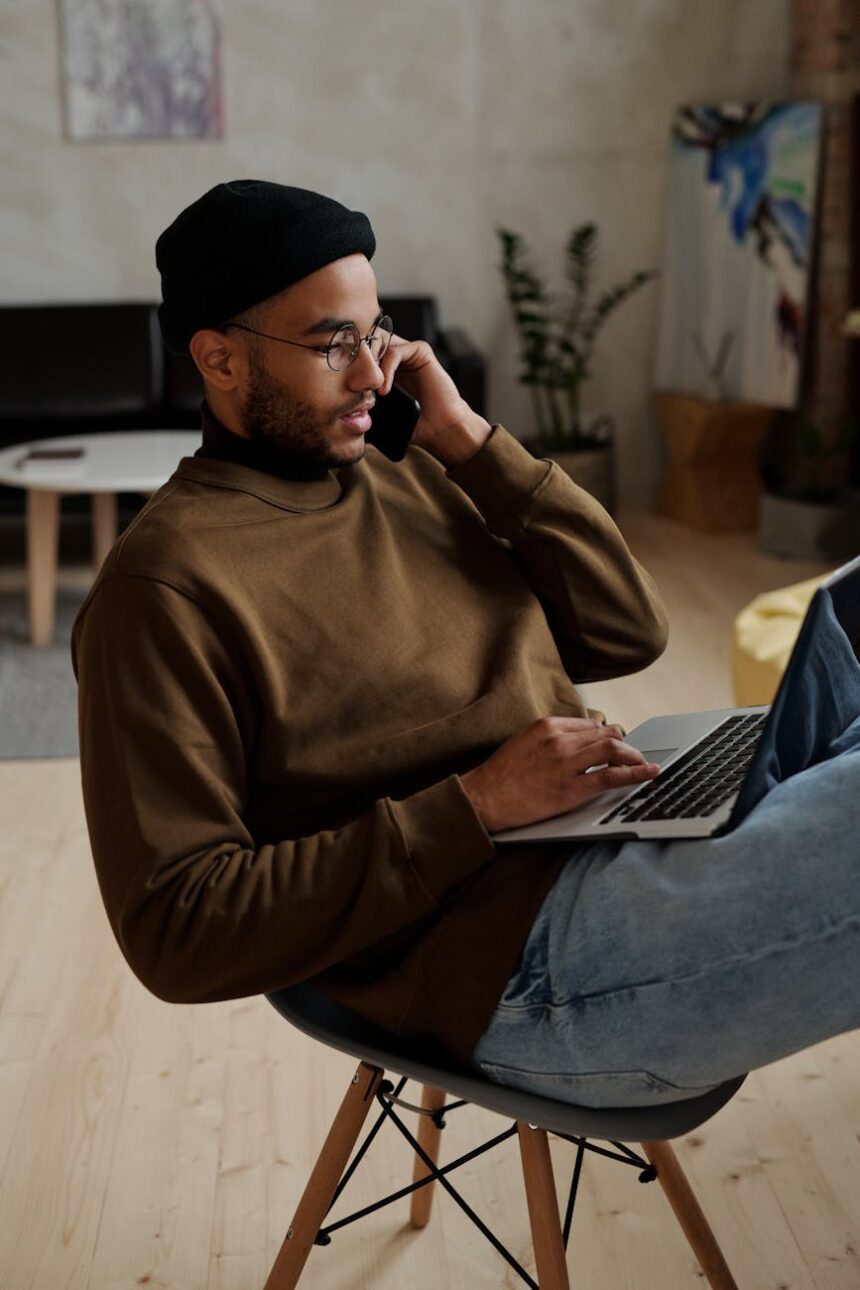 A focused student works on a laptop in a cozy cafe, with a notebook and coffee nearby.