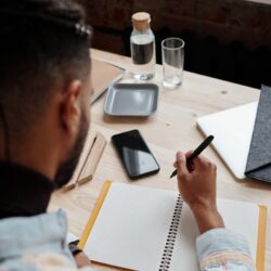 A student's desk with an open laptop displaying graphs next to a handwritten notebook, symbolizing the digital vs analog choice.