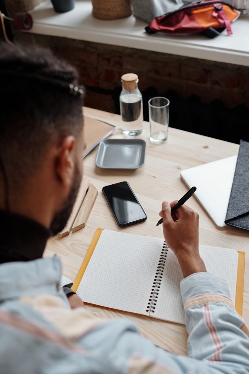 A student's desk with an open laptop displaying graphs next to a handwritten notebook, symbolizing the digital vs analog choice.