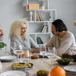 A diverse group of friends enjoying a lively potluck dinner in a warmly lit apartment.