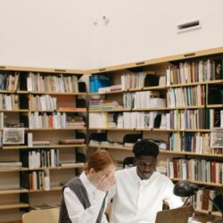 A recent graduate sits at their kitchen table, looking thoughtfully at their student loan information on a laptop.