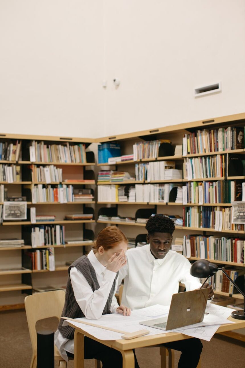 A recent graduate sits at their kitchen table, looking thoughtfully at their student loan information on a laptop.