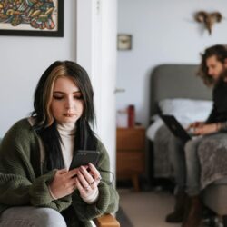 A young adult smiling while checking their bank balance on a modern mobile banking application.