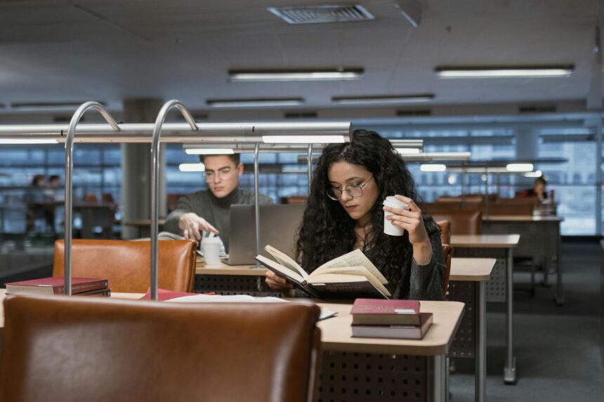 A focused student sitting at a wooden desk, surrounded by open books and highlighting notes.