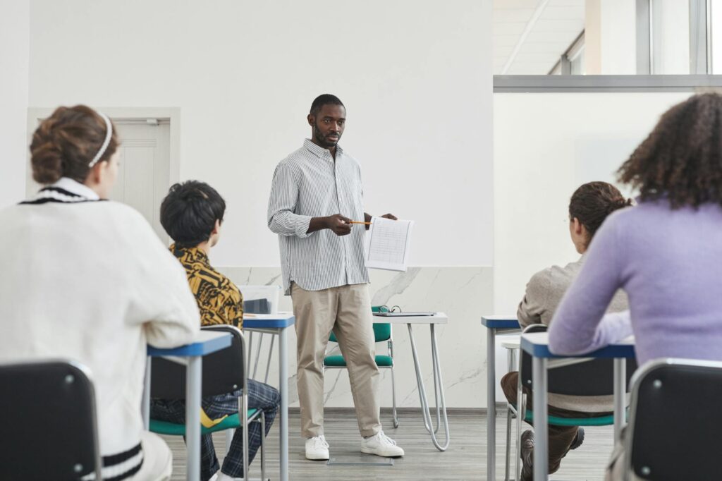 A multi-ethnic group of college students actively participating in a seminar, one student is speaking while others listen attentively.