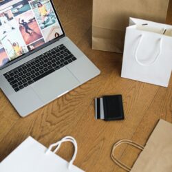 A focused college student sitting in a dorm room, examining a credit card while working on a laptop.