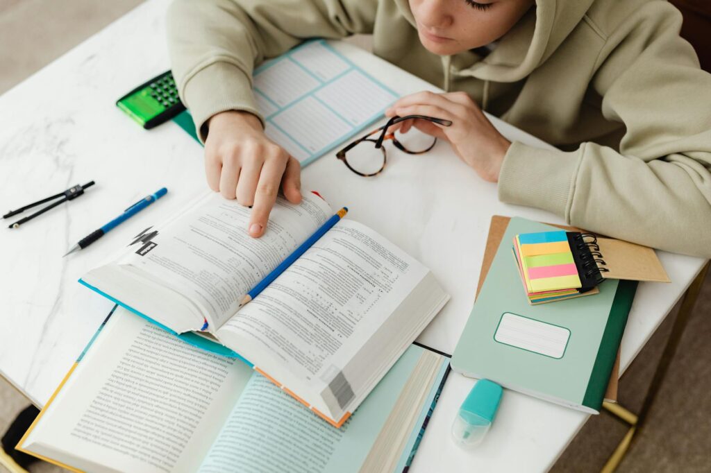 Close-up of a student's hand using a yellow highlighter on a textbook page.