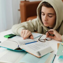 A diligent student highlights an important passage in a thick university textbook.