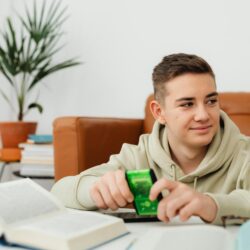 A focused student reviewing a stack of colorful index cards at a well-lit desk.