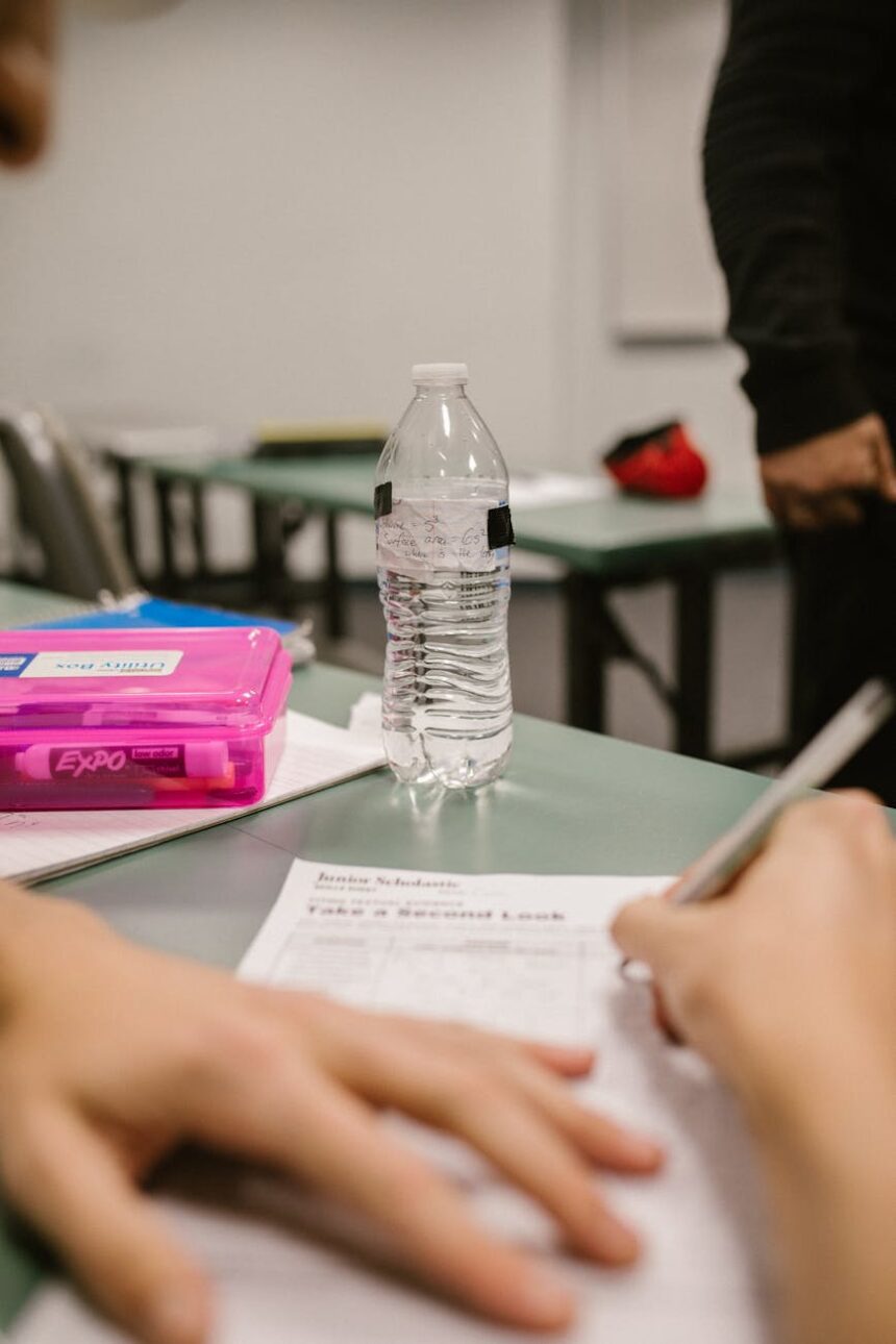 A university student focused intently on writing an essay during a timed exam in a large hall.