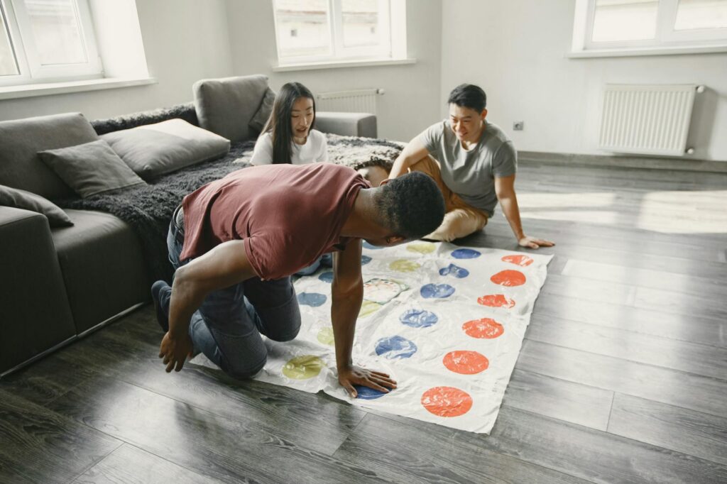 Four friends focused and laughing while playing a complex board game in a cozy living room.