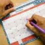 A university student diligently organizes their semester schedule using a physical planner and a digital calendar on their laptop.