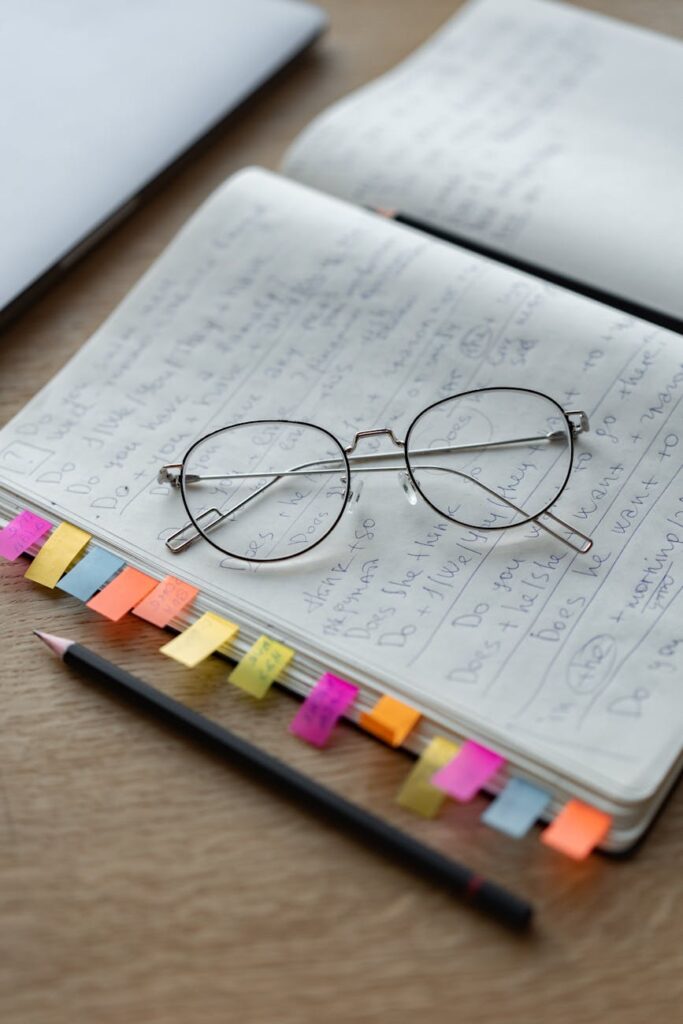 Close-up of a student's hands writing down academic goals in a daily planner with colorful sticky notes.