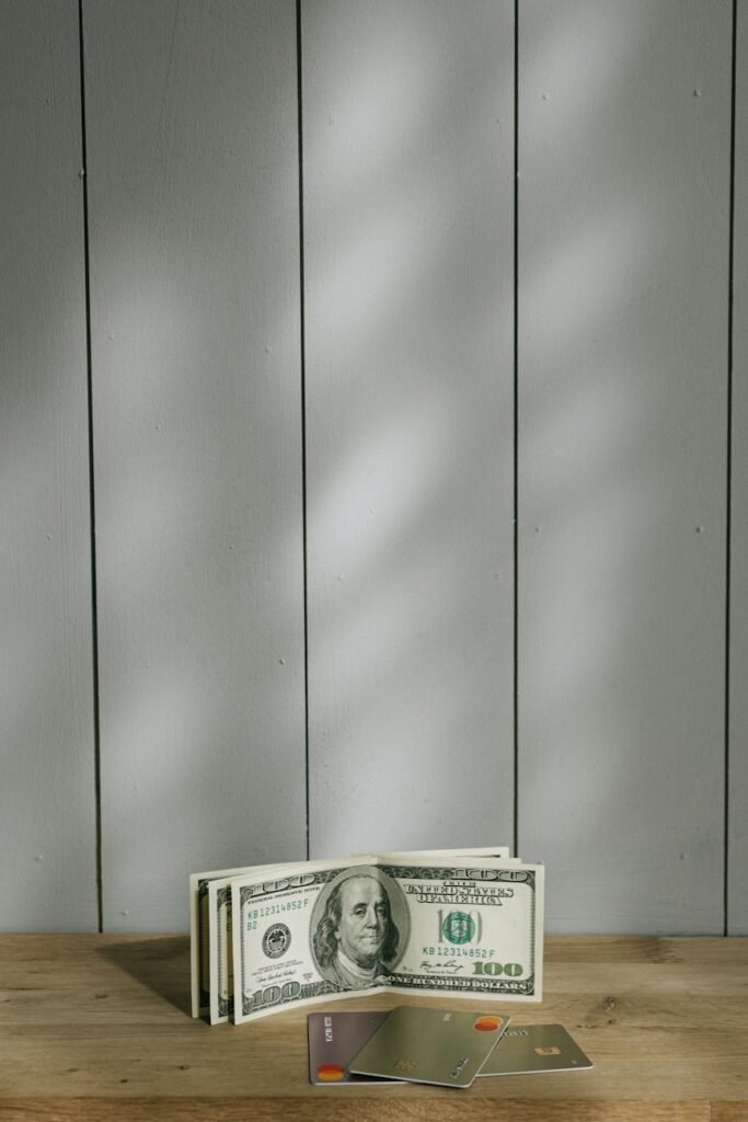 A bright pink piggy bank sitting next to a blue credit card on a clean wooden surface, illustrating financial responsibility.