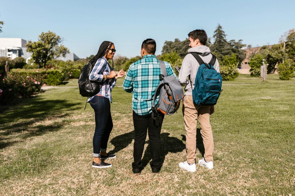 A diverse group of smiling university students chatting and laughing together on a campus lawn.