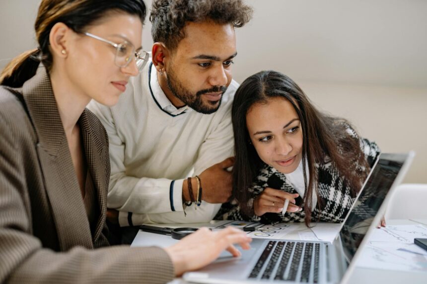 A young professional smiles with relief while working on a laptop, symbolizing the weight of student loan forgiveness.