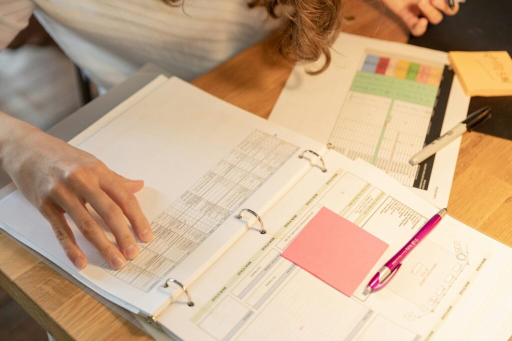 A stack of student loan paperwork next to a calculator and a pen, illustrating the process of managing debt for PSLF.