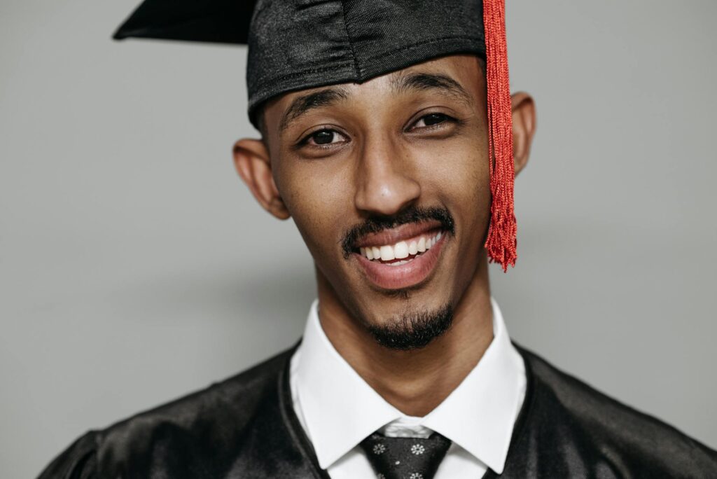 A black graduation cap rests on a rolled-up diploma, symbolizing the cost and achievement of higher education.