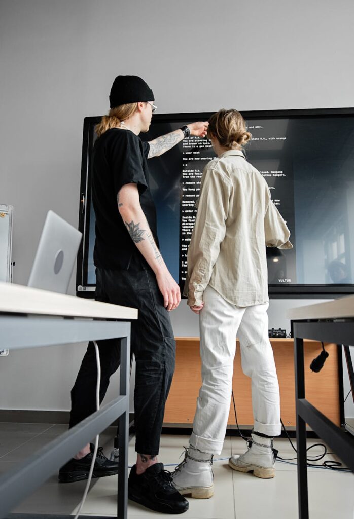 A close-up shot of a student's hands arranging a graphic design portfolio on a high-resolution computer monitor.
