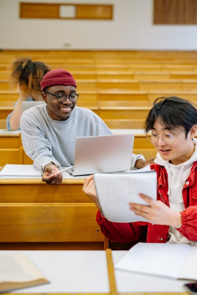 A diverse group of smiling college students working together on a laptop in a modern library.