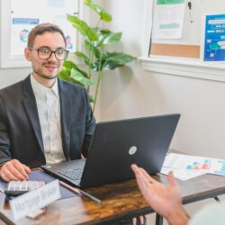 A friendly career advisor points to a resume while talking with a college student in a bright office.