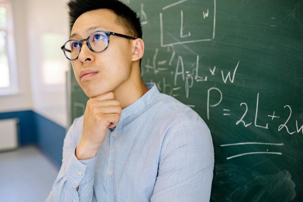 A focused college student actively listening and taking notes in a university lecture hall.