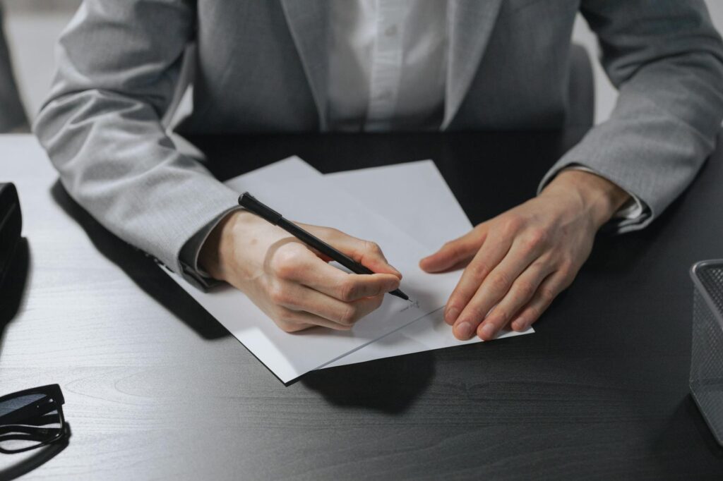 A close-up shot of a person's hand carefully signing a personal loan agreement form.
