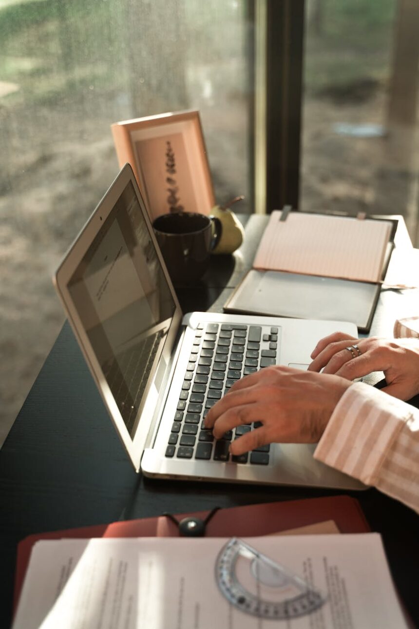 A young student diligently studying at a clean, sunlit desk with their laptop and an open notebook.
