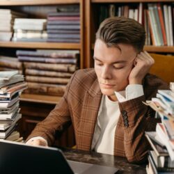 A focused college student sits at a desk, mapping out their career roadmap on a laptop and in a notebook.